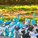 A stampede of happy felt plushie cats in a park during the day, captured in a long shot. (2).webp