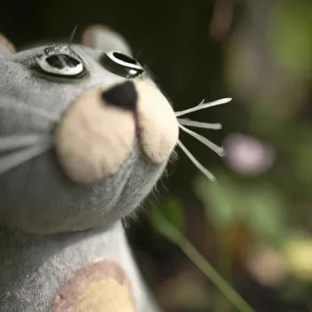 A vintage felt plushie cat in a garden looks with curiosity at something above, macro photogra...jpg